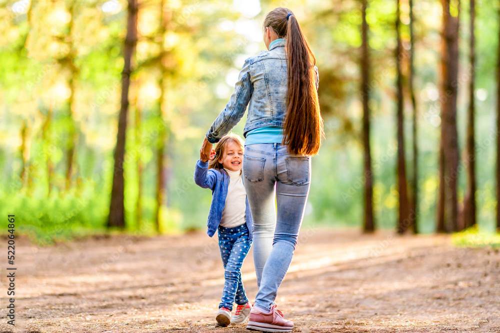 Young mother and daughter having fun in the forest. Summer sunny day. Playful mood Young mother and daughter having fun in the forest. Summer sunny day. Playful mood