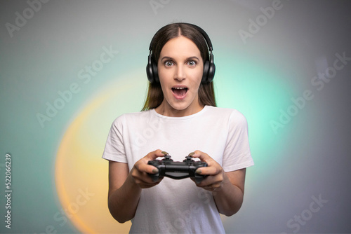 Game win. Happy female gamer in headphones rejoices in the victory in the game. Emotional gamer. Portable game console