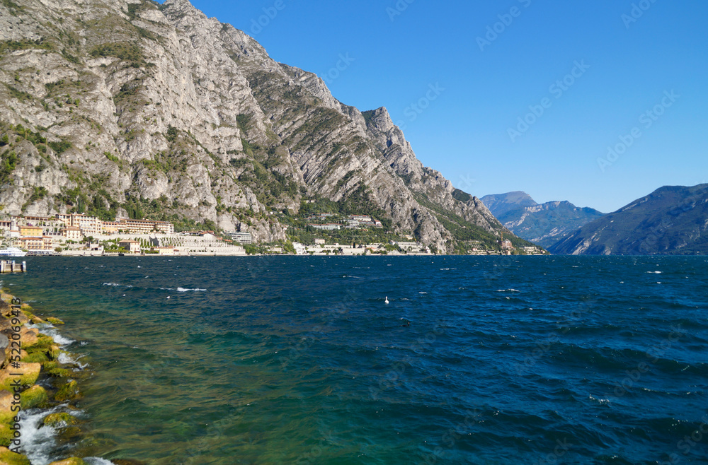 Fototapeta premium a beautiful old harbor in the Italian town of Limone sul Garda on turquoise lake Garda with mountains in the background (Lombardy)
