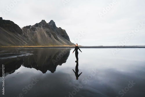 woman and her reflection on reflecting beach against mountains photo