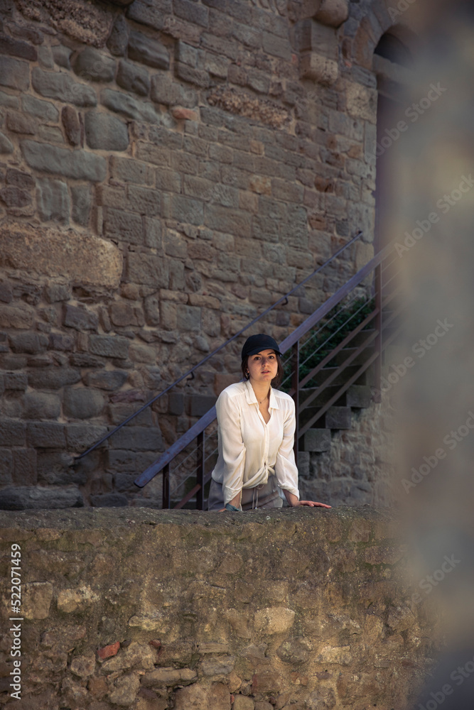Pretty girl in a white shirt leaning against a castle wall