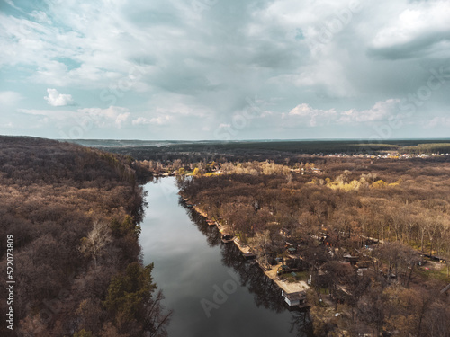 Aerial view on river curve in bare trees forest with epic cloudy sky. Nature landscape from drone near Koropove village in Kharkiv region. Color graded © Kathrine Andi