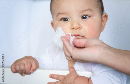 Fotografi Mom wipes the baby's drool with a napkin