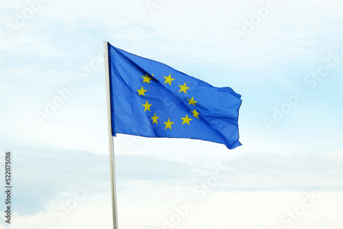The Flag of Europe. Circle of 12 stars on blue background waves on blue sky. EU flag