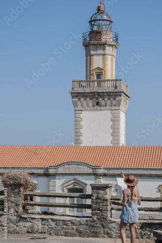 Girl drawing a red lighthouse on a summer day