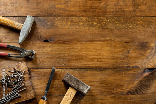 Different carpentry tools on a wooden background. Nail puller, chisel, two hammers, nails on a wooden board. Copy space.