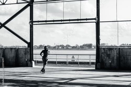 Black and White Photo of a Roller Skater in Silhouette in Crescent Park with a View of the Mississippi River and the West Bank on January 9, 2022 in New Orleans, Louisiana, USA photo