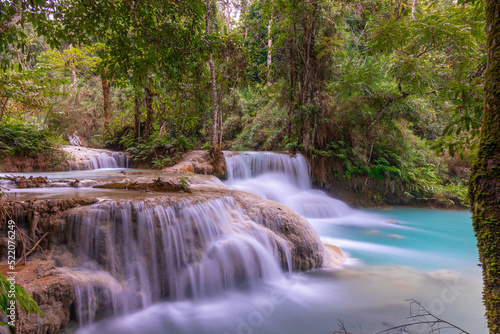 Magical turquoise blue colours of Kuang Si waterfalls Luang Prabang Laos. these waterfalls in the Mountains of Luang Prabang Laos flow all year round in the natural national park rainforest 