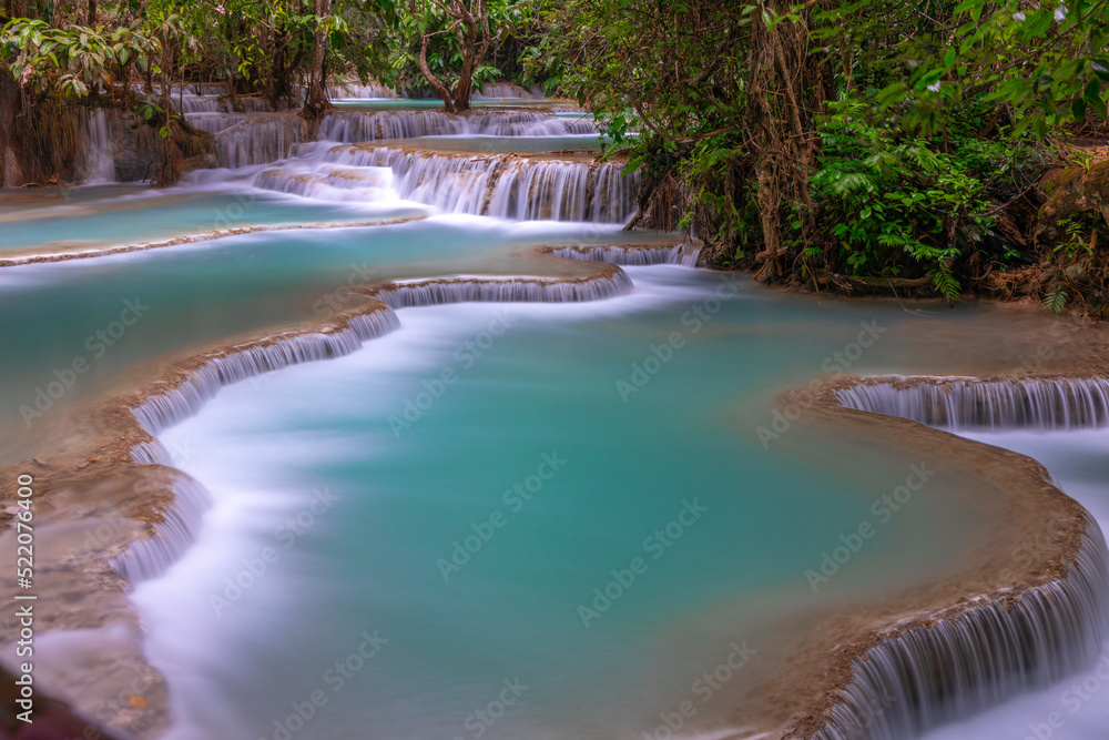 Magical turquoise blue colours of Kuang Si waterfalls Luang Prabang Laos. these waterfalls in the Mountains of Luang Prabang Laos flow all year round in the natural national park rainforest 