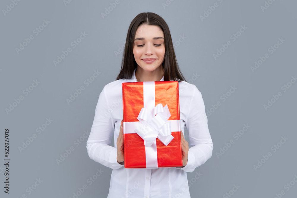 Surprised woman holding gift. Smiling beautiful young brunette woman in shirt hold present box with gift ribbon bow isolated on bright gray background, studio portrait. Birthday concept. Surprised woman holding gift. Smiling beautiful young brunette woman in shirt hold present box with gift ribbon bow isolated on bright gray background, studio portrait. Birthday concept.