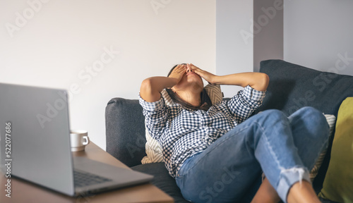 Tired from work young woman in front of a laptop. photo