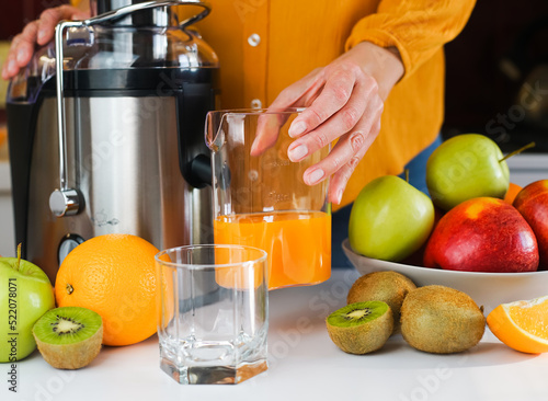 Cuadro en lienzo A young woman prepares healthy fruit juice in the kitchen at home