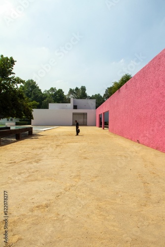 An architectural work of Luis Barragan with smooth pink and white walls beside a pool under open sky photo
