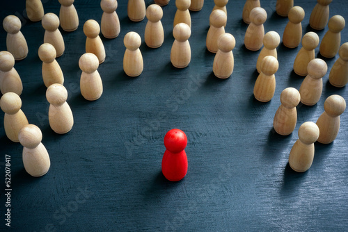 Discrimination and inclusion concept. The wooden figurines surrounded the red one.