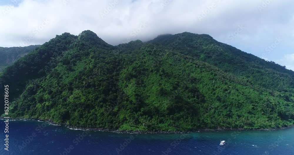 Aerial shot of a boat along the rocky coast of a tropical island Aerial shot of a boat along the rocky coast of a tropical island
