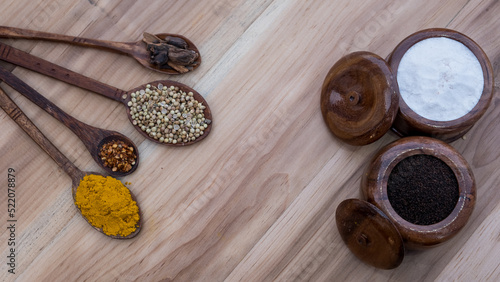 Top view of four old spoons with spices, herbs beans and cinnamon food wooden texture background arrangement.