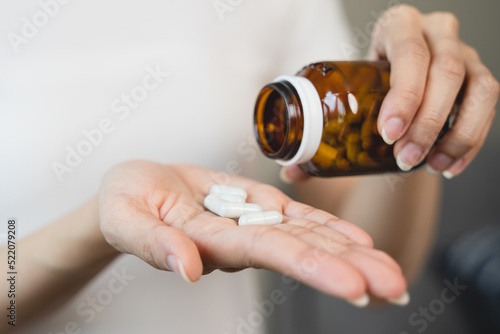 close up person pouring multivitamin capsules to her hands