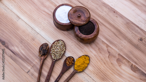 Top view of four old spoons with spices, herbs beans and cinnamon food wooden texture background arrangement.
