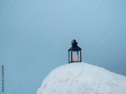 An old candle lantern stands on the evening snow in frosty winter.