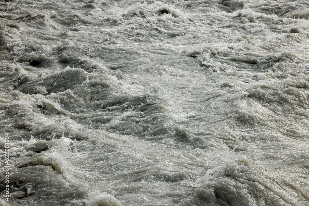 Dirty flood water flowing rapidly in a mountain river