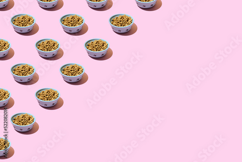 Pattern. Cat dry food in a bowl on a pink background. The concept of a diet for pets, the choice of food for cats. Copy space, minimalism.