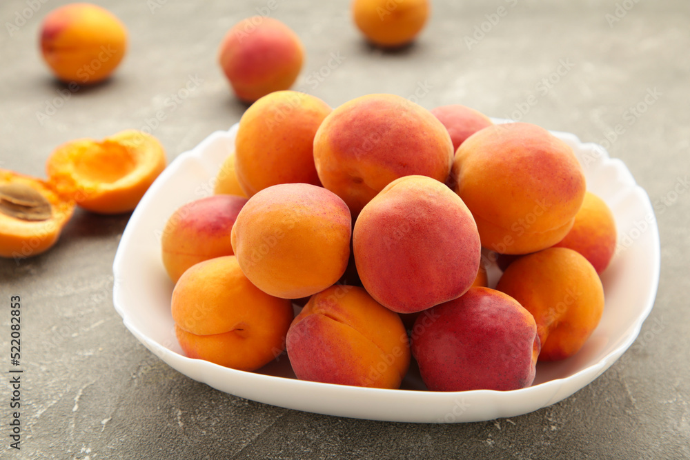 Fresh apricots in the bowl on grey concrete background Fresh apricots in the bowl on grey concrete background