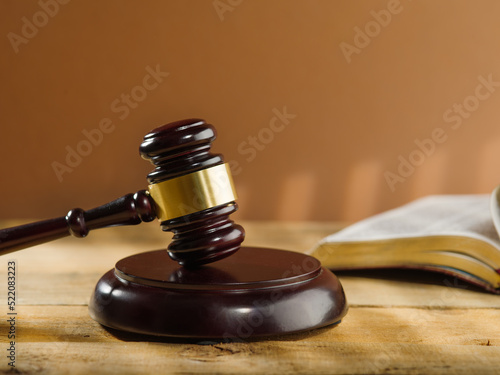 Close-up. Wooden judge's gavel and an open book on a beige background. Court and justice, Constitution, Bible, rule of law. There are no people in the photo. Banner, advertising. poster.