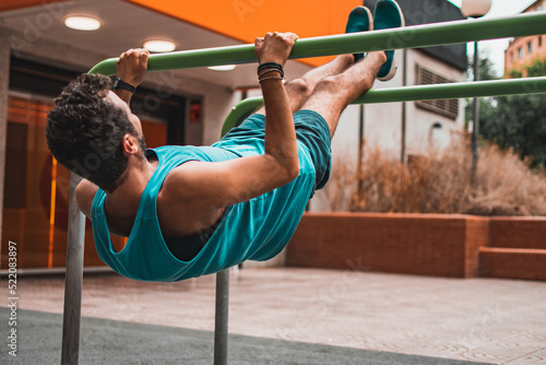 Obraz na plátně Back view of a beginner caucasian man doing calisthenics workout in outdoor bars