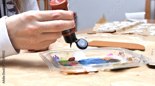 a woman painting some wooden figures with brushes