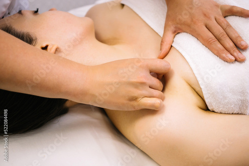 Woman receiving facial massage with gua sha tool in beauty salon. Beauty and skincare concept with a beautiful woman. Middle aged female using guasha. Massage for facial lifting