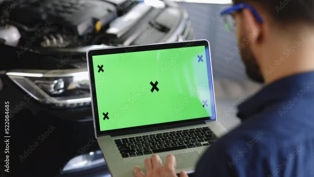 Car service mechanic uses laptop computer with green screen mock up chroma key car diagnostic software. Car Scanner Computer Diagnostics. Automotive Electronic Diagnostic Car service mechanic uses laptop computer with green screen mock up chroma key car diagnostic software. Car Scanner Computer Diagnostics. Automotive Electronic Diagnostic
