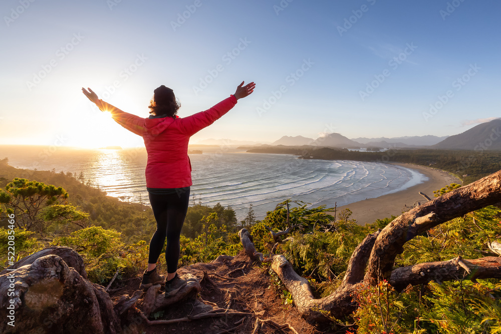 Adventurous Woman Hiker overlooking Sandy Beach on the West Coast of Pacific Ocean. Canadian Nature Landscape Background. Cox Bay Lookout, Tofino, Vancouver Island, BC, Canada. Adventurous Woman Hiker overlooking Sandy Beach on the West Coast of Pacific Ocean. Canadian Nature Landscape Background. Cox Bay Lookout, Tofino, Vancouver Island, BC, Canada.