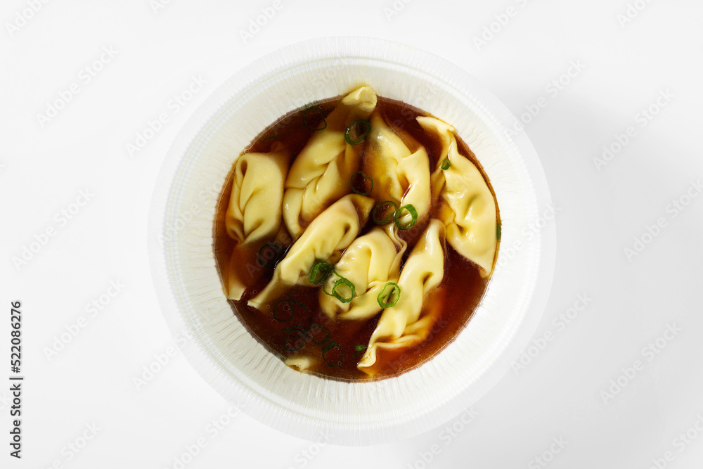 asian steamed dumplings served in chili broth on a white table in a box for delivery