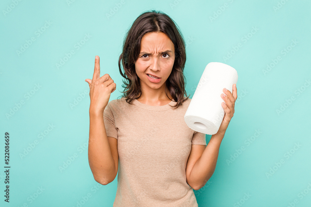 Young hispanic woman holding kitchen roll isolated on blue background showing a disappointment gesture with forefinger. Young hispanic woman holding kitchen roll isolated on blue background showing a disappointment gesture with forefinger.