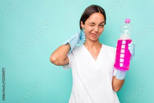 Young cleaner hispanic woman isolated on blue background touching back of head, thinking and making a choice.