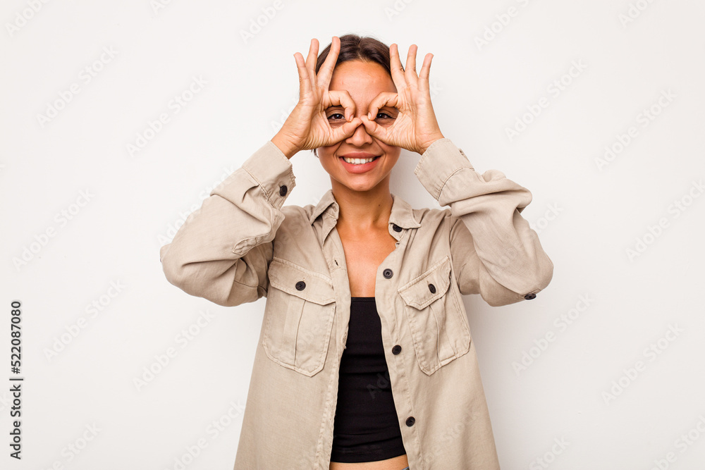 Young hispanic woman isolated on white background showing okay sign over eyes Young hispanic woman isolated on white background showing okay sign over eyes