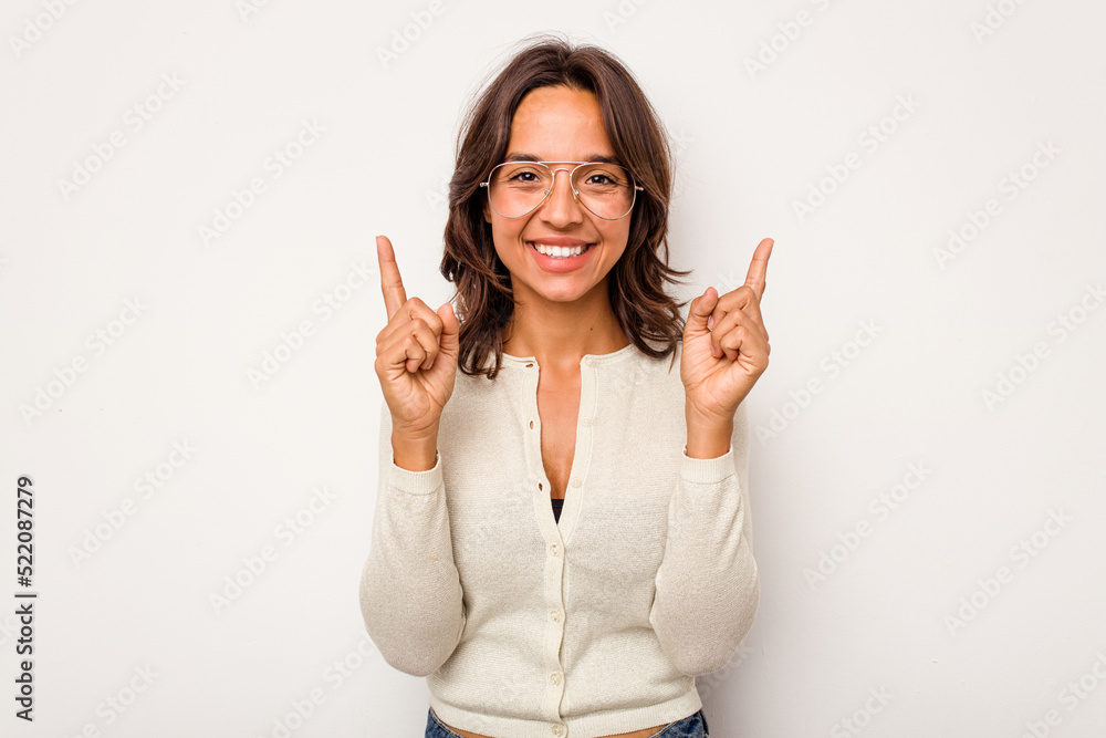 Young hispanic woman isolated on white background indicates with both fore fingers up showing a blank space. Young hispanic woman isolated on white background indicates with both fore fingers up showing a blank space.