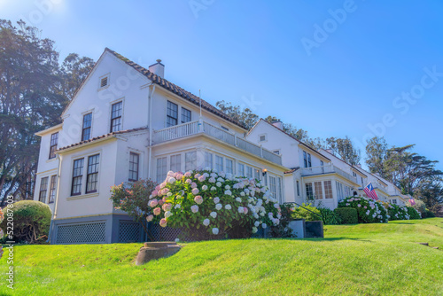 Suburban houses on a sloped green lawn with flowering plants near the entrance in San Francisco, CA