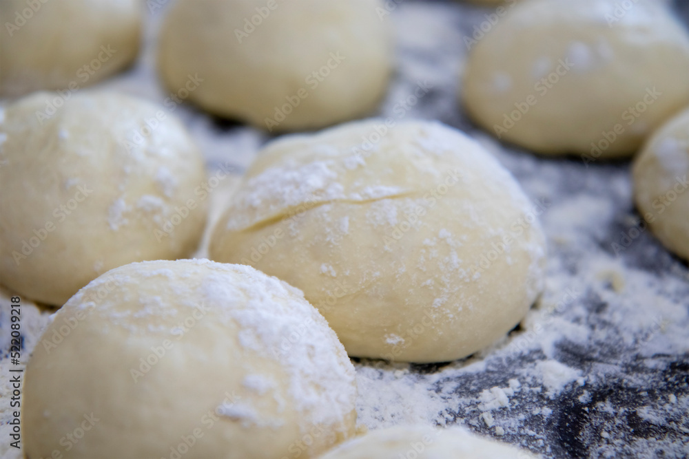 selective focus on small and neat balls of air dough for baking sweet pies and buns. The concept of home cooking. Blurred background