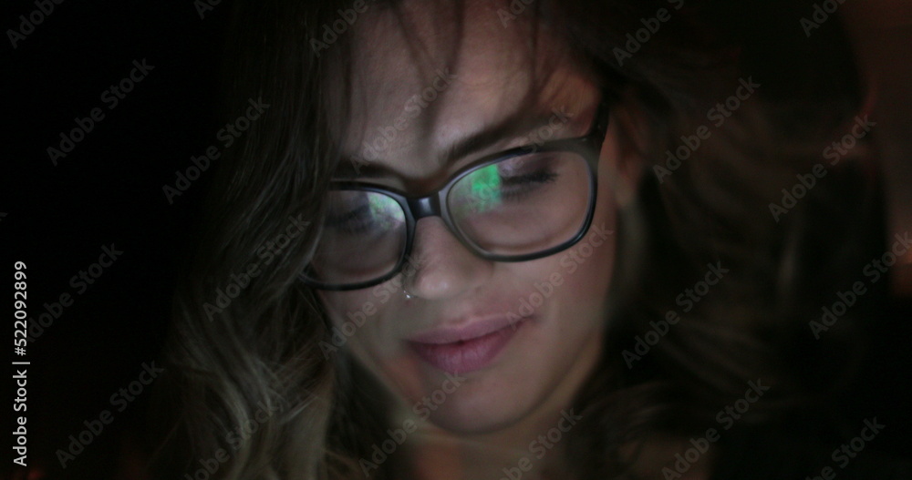Young woman looking at cellphone in the back seat of a car. Girl wearing glasses riding taxi tab starring at tablet screen Young woman looking at cellphone in the back seat of a car. Girl wearing glasses riding taxi tab starring at tablet screen