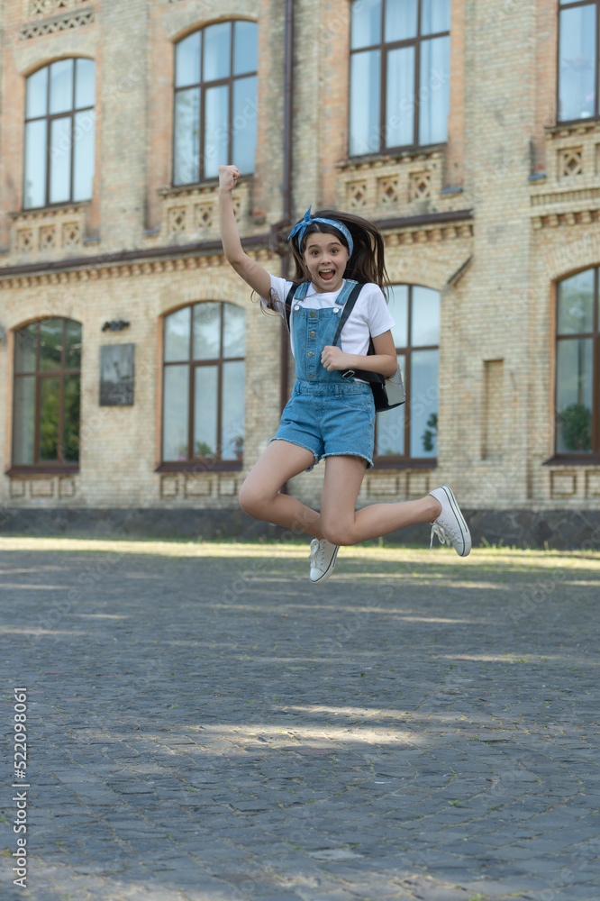 glad denim girl with backpack jumping outdoor