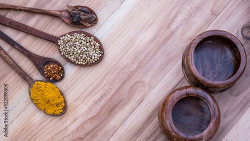 Top view of four old spoons with spices, herbs beans and cinnamon food wooden texture background arrangement.