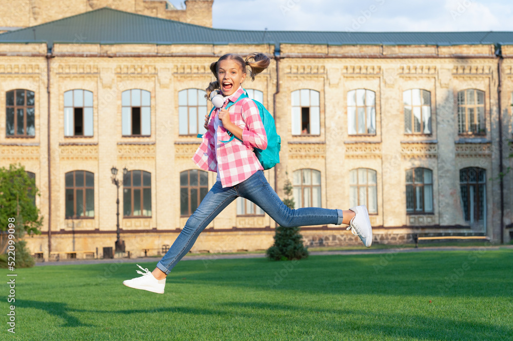 Happy active teenage girl jumping in school yard outdoors