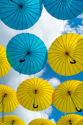 Blue and yellow umbrellas hanging bottom-up sky background