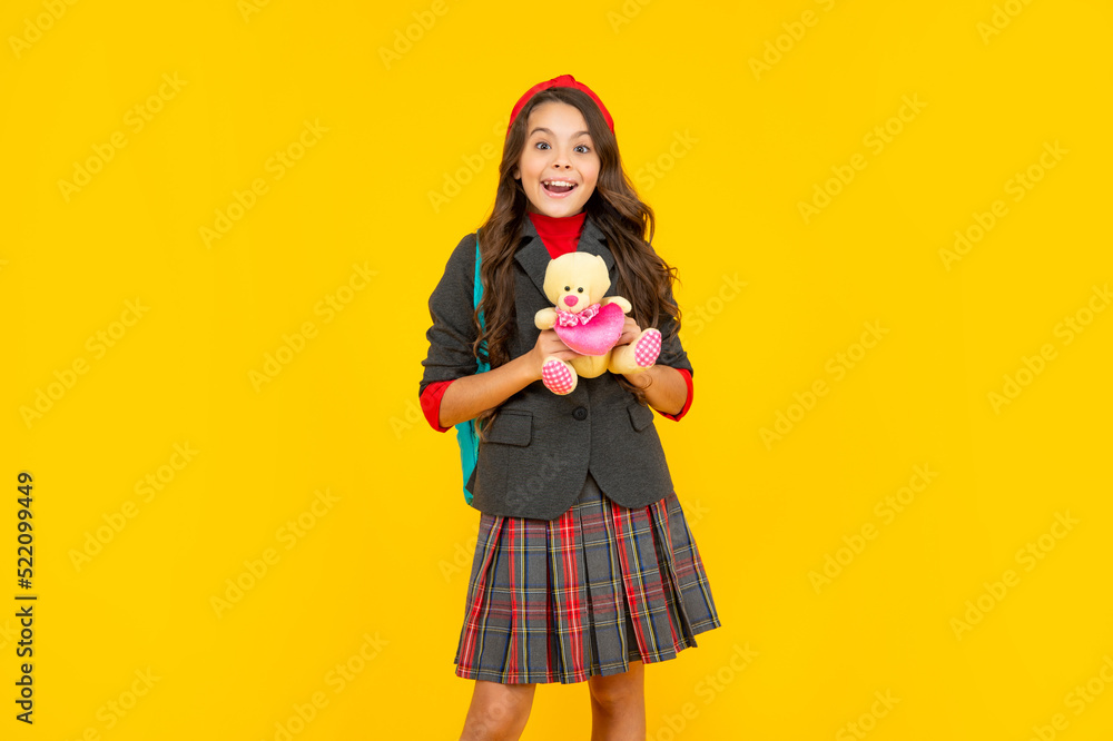 positive teen girl in uniform holding toy on yellow background, childhood positive teen girl in uniform holding toy on yellow background, childhood