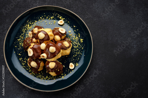 фотографія Profiteroles dessert with hazelnuts on a black background