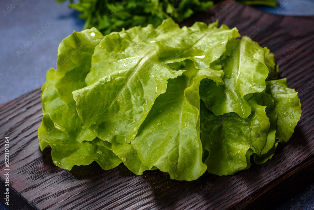 Salad, parsley and dill on a dark cutting board against a blue concrete background Salad, parsley and dill on a dark cutting board against a blue concrete background