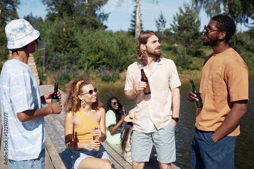 Diverse group of young people enjoying refreshing drinks outdoors in Summer © Seventyfour