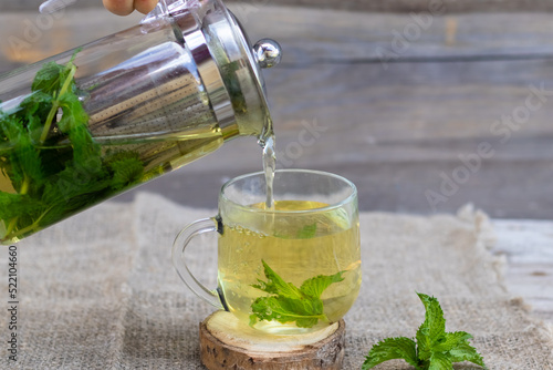 A teapot with mint tea and a mug on a wooden background.A soothing, healthy drink.Summer tea