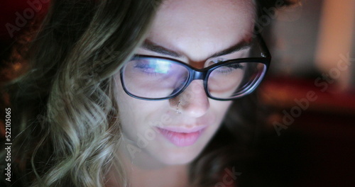 Young woman at night in the back seat of a car looking at cellphone